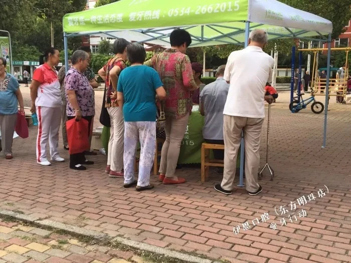社区老年居民在公益服务点排队咨询口腔问题。
