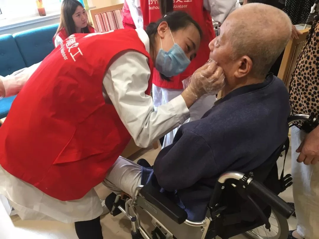 义工人员为轮椅上的高龄老人提供口腔健康服务。